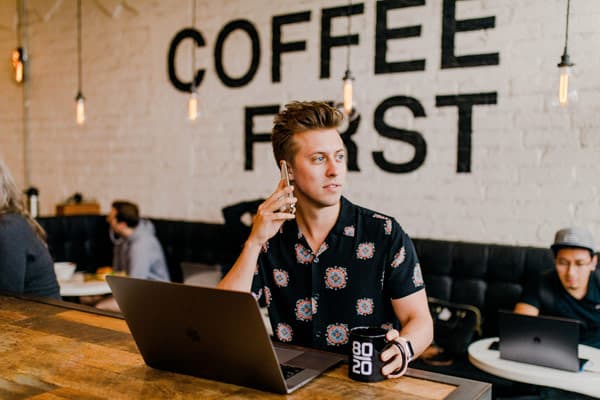 Junger Mann im Kaffee verdient Geld mit Social-Media